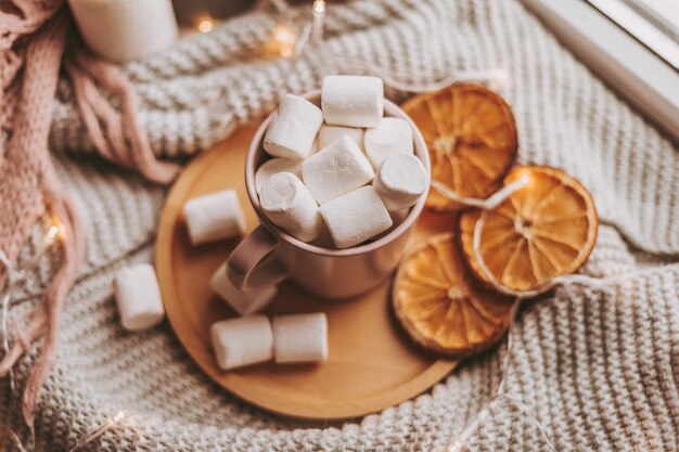 Copo rosa com marshmallows em uma bandeja de madeira e fatias de frutas cítricas