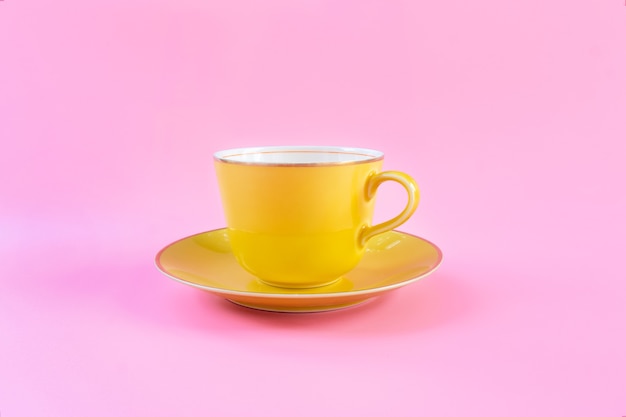 Copo vazio amarelo sobre fundo rosa pastel. Caneca amarela vazia em branco para café ou chá. conceito relaxe