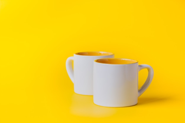 Copo vazio de café ou chá branco com amarelo sobre fundo amarelo. copie o espaço para o texto.