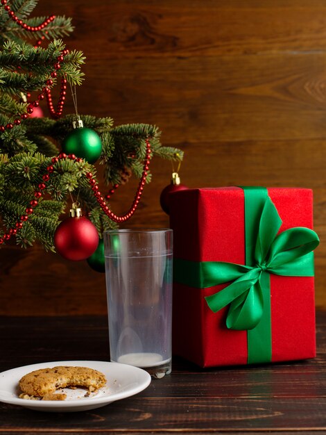 Copo vazio de leite e biscoitos e um presente debaixo da árvore de Natal