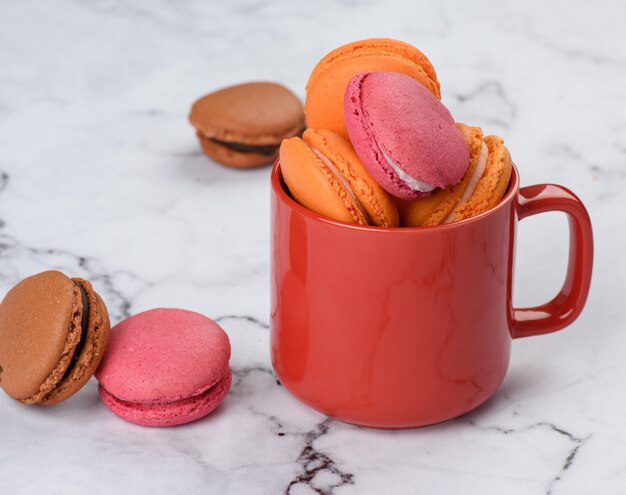 Copo vermelho e macarons assados em uma mesa branca, close-up