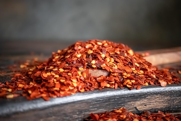 Copos de ají rojo picante en primer plano de una cuchara de madera sobre una mesa de cocina.