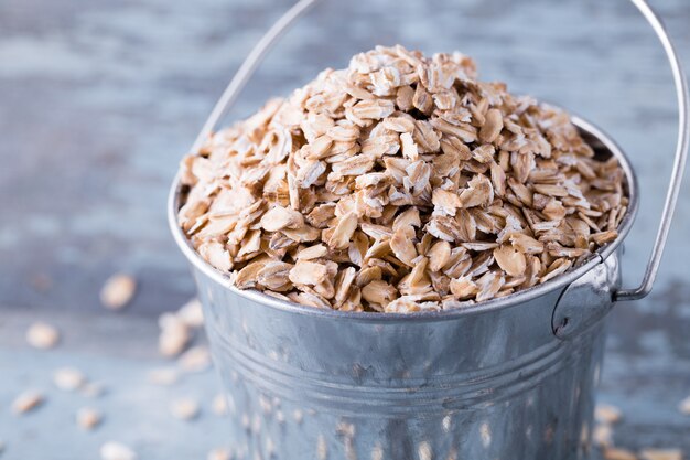 Copos de avena cruda en un cubo sobre madera