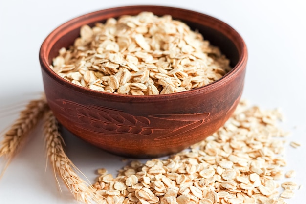 Copos de avena en un recipiente aislado en blanco