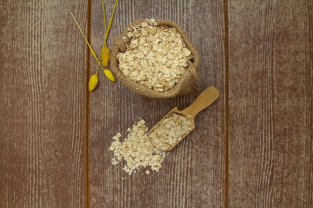 Copos de avena en un saco y una cuchara sobre la mesa de madera