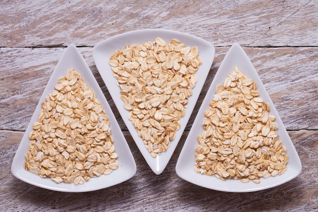 Copos de avena en un tazón blanco sobre una mesa de madera