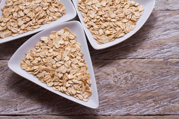 Copos de avena en un tazón blanco sobre una mesa de madera