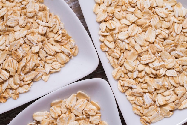 Copos de avena en un tazón blanco sobre una mesa de madera