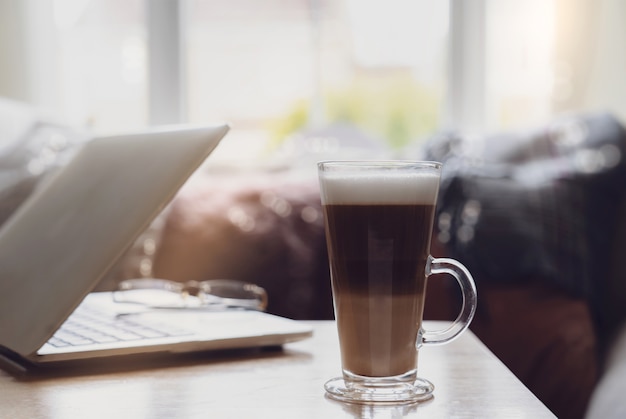 Copos caseiros de grãos de café com leite e laptop na mesa de café no espaço de trabalho ou cena aconchegante de relaxamento no intervalo da tarde com café e notebook na sala de estar