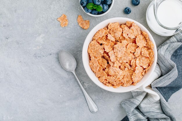 Copos de cereales integrales para el desayuno con arándanos frescos y leche Tazón de desayuno saludable Espacio de copia de vista superior