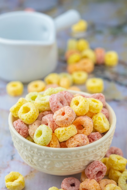 Foto copos de cereales en un tazón blanco con espacio de copia, concepto de desayuno. alimentos con delicioso sabor afrutado y colores afrutados. está hecho con maíz, trigo y cebada.