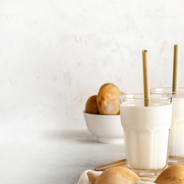 Copos com leite de batata vegano com canudos de bambu em pano de fundo neutro claro Copiar espaço