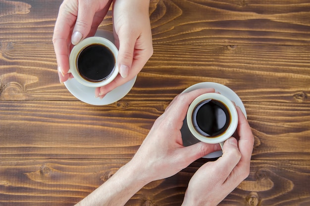 Copos com um café nas mãos de homens e mulheres.