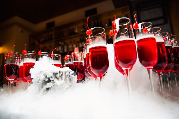 Copos com uma bebida vermelha estão no balcão o copo é decorado com cerejas