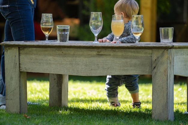 Copos de bebidas em uma mesa de madeira vintage contra um bebê infantil e pai Festa da família no jardim