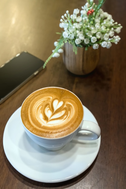 Copos de café na mesa com falso decorar flor falsa e telefone celular