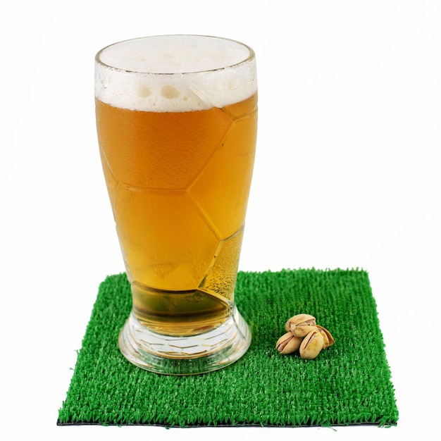 Copos de cerveja e punhado de pistaches na grama verde à mesa