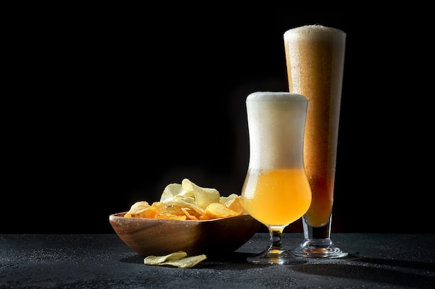 Copos de cerveja escura e clara com batatas fritas