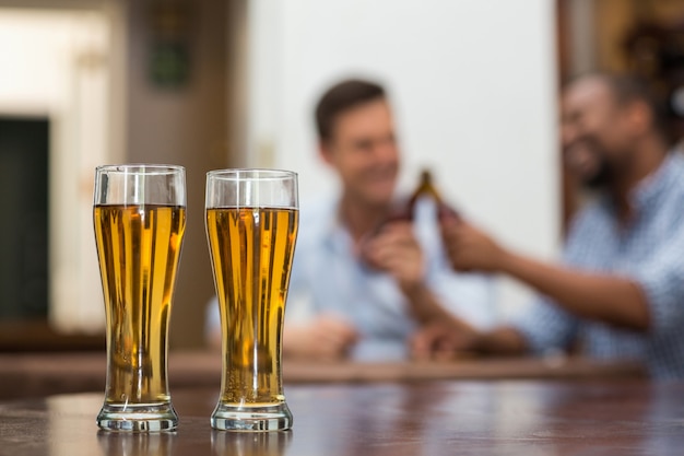 Copos de cerveja mantidos na mesa de madeira