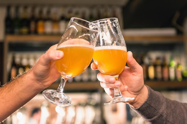 Foto copos de cerveja para amigos a fazerem um brinde no bar.