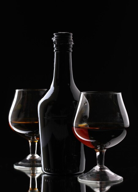 Copos de conhaque e garrafa em fundo preto