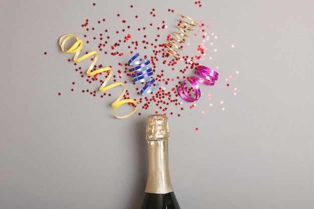 Copos de garrafa de champanhe e confetes em uma vista superior de fundo colorido