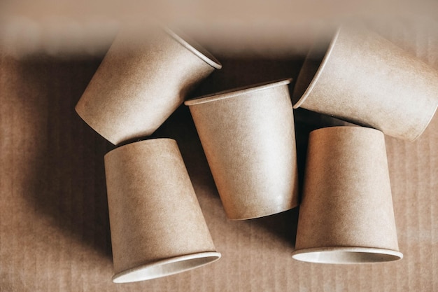 Copos de papel descartáveis em fundo de papel kraft Utensílios de mesa descartáveis ecologicamente corretos