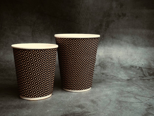 Copos de papel para viagem de café na mesa isolados em fundo de concreto