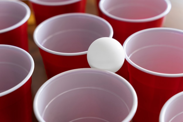 Copos de plástico de close-up e bola usados para cerveja pong em uma festa