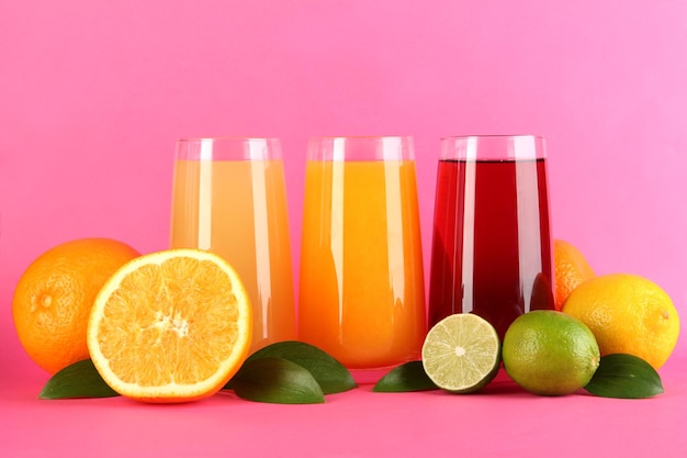 Copos de suco com folhas e frutas no fundo rosa