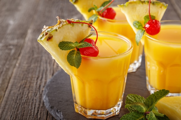 Copos de suco de abacaxi com pedaços de abacaxi