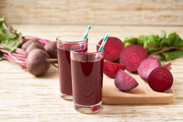 Copos de suco de beterraba com legumes em uma mesa de madeira. Beterraba fresca e suco