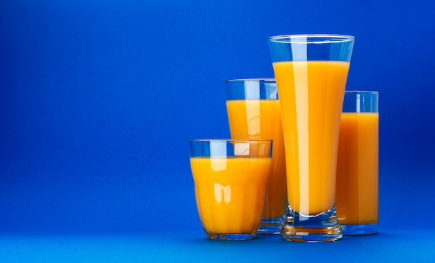 Copos de suco de laranja em fundo azul com espaço de cópia