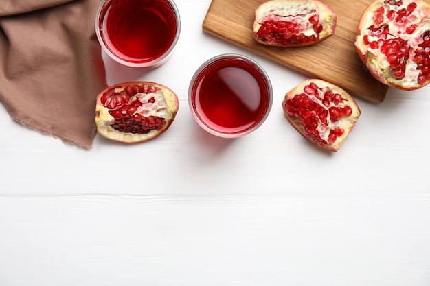 Copos de suco de romã na mesa de madeira branca plana Espaço para texto