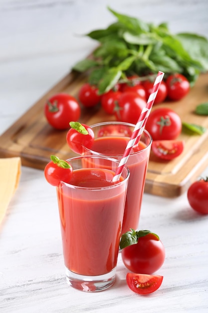 Copos de suco de tomate com vegetais em uma mesa de madeira de perto