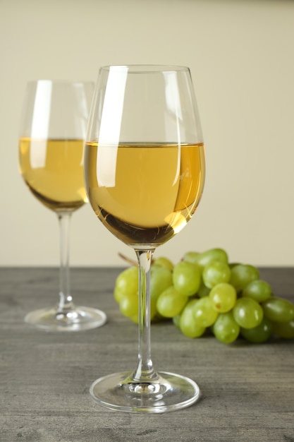Copos de vinho branco e uva na mesa cinza texturizada