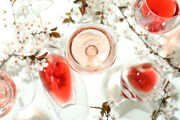Copos de vinho e flores de cerejeira em fundo branco