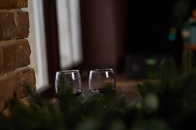 Copos de vinho em casa Atmosfera de Natal no parapeito da janela Primeiro plano desfocado Espaço para cópia Cartão festivo discreto ou plano de fundo