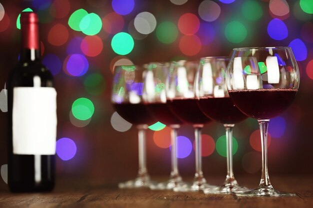 Copos de vinho em linha na mesa de madeira contra luzes desfocadas