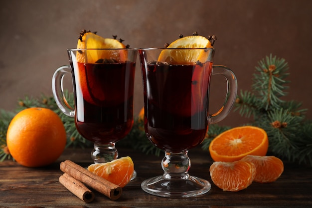 Copos de vinho quente saboroso com laranja na mesa de madeira