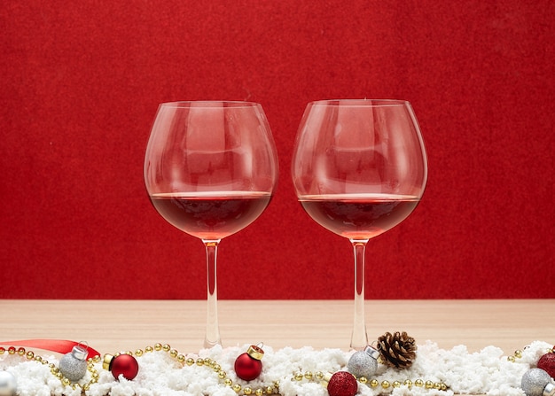 Copos de vinho tinto e bolas de Natal na neve