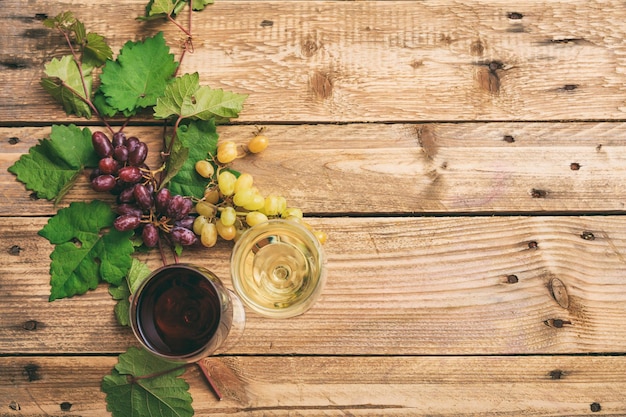 Copos de vinho tinto e branco e uvas frescas no espaço de cópia de fundo de madeira