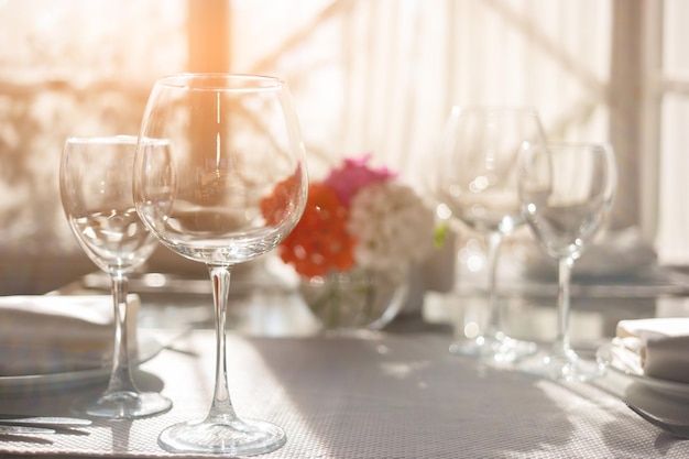 Copos de vinho vazios em copos de toalha de mesa branca e sol convidam amigos para almoçar a clea perfeita