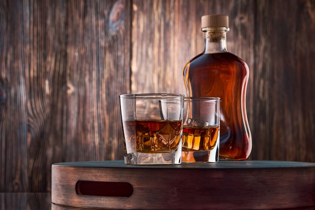 Copos de whisky e uma garrafa na mesa de madeira