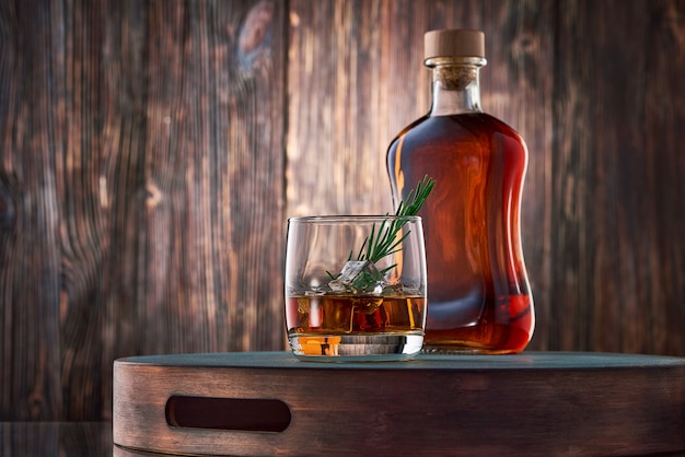 Foto copos de whisky e uma garrafa na mesa de madeira