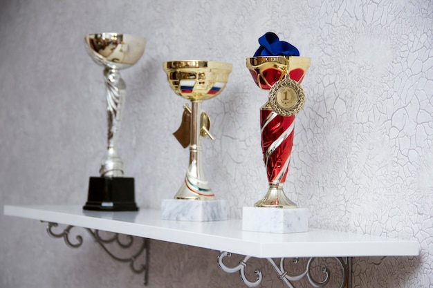 Copos e prêmios na prateleira. o prêmio é um troféu para o vencedor da exposição na prateleira.