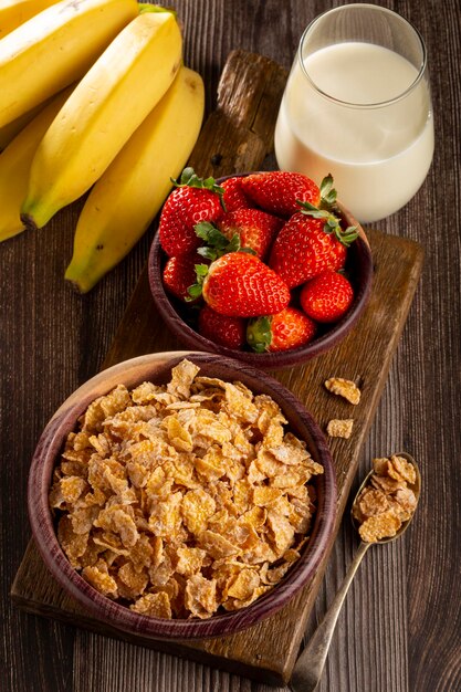 Copos de maíz en el bol con bayas y leche sobre la mesa