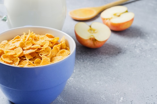 Copos de maíz en una taza azul y rodajas de manzana. Desayuno útil en la mañana. Copia espacio