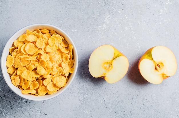 Foto copos de maíz en una taza azul y rodajas de manzana. desayuno útil en la mañana. copia espacio