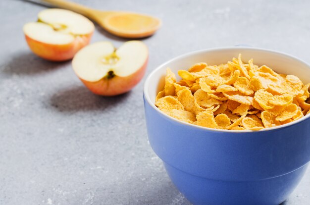 Copos de maíz en una taza azul y rodajas de manzana